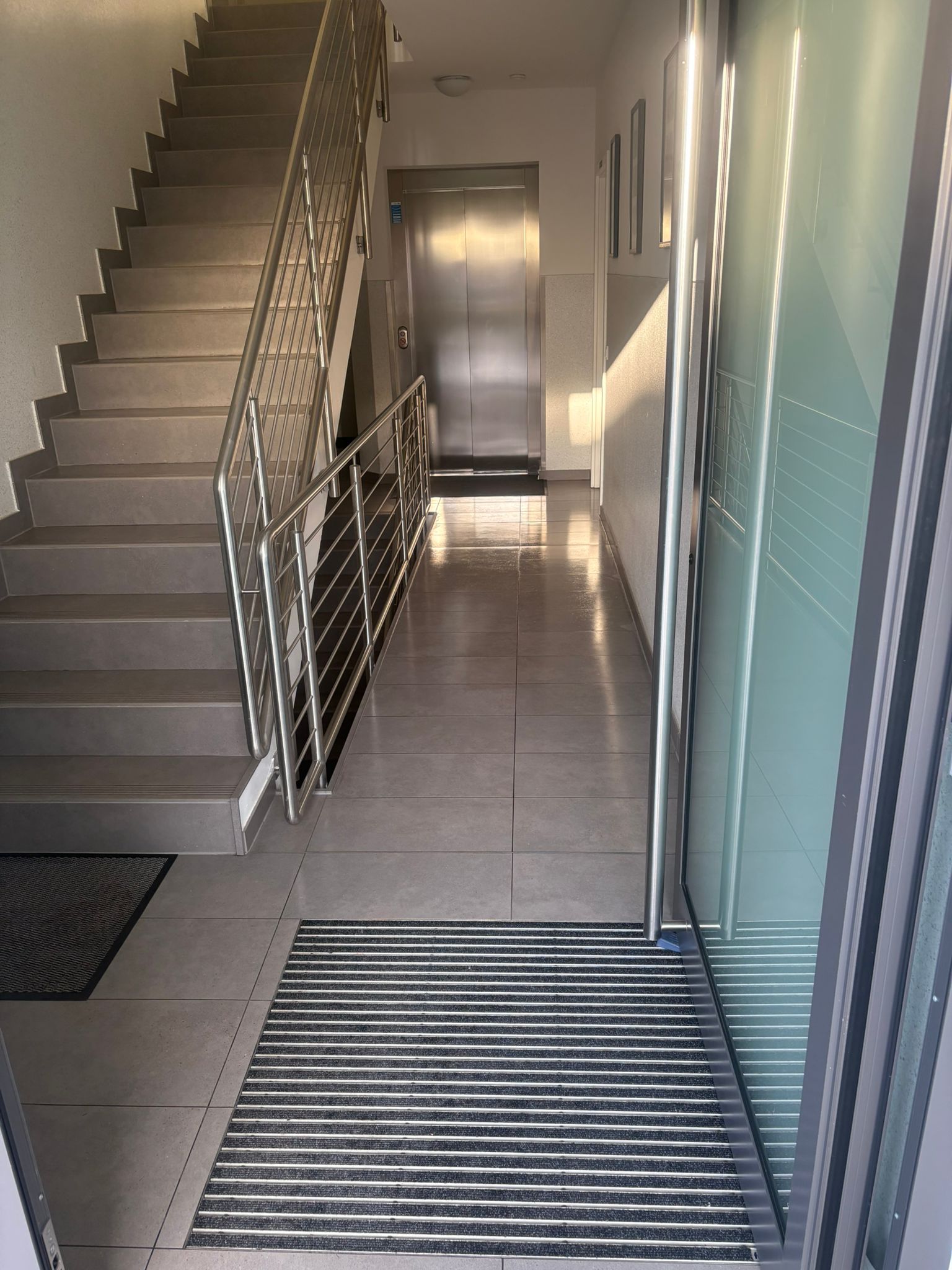 Gereinigtes Treppenhaus mit Fliesenboden und Fußmatte
